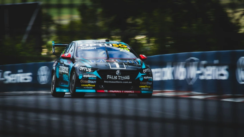 a car racing along a race track with trees in the background