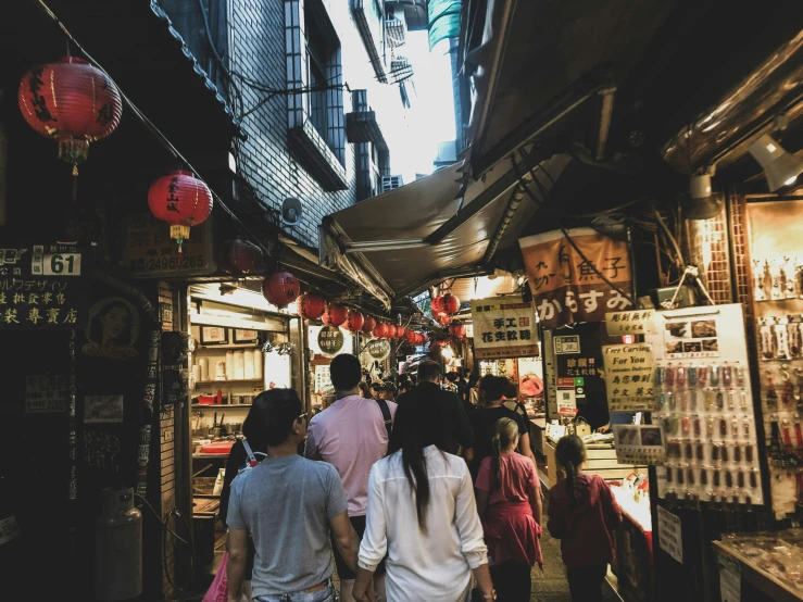 the narrow asian city has people walking around and shops on it