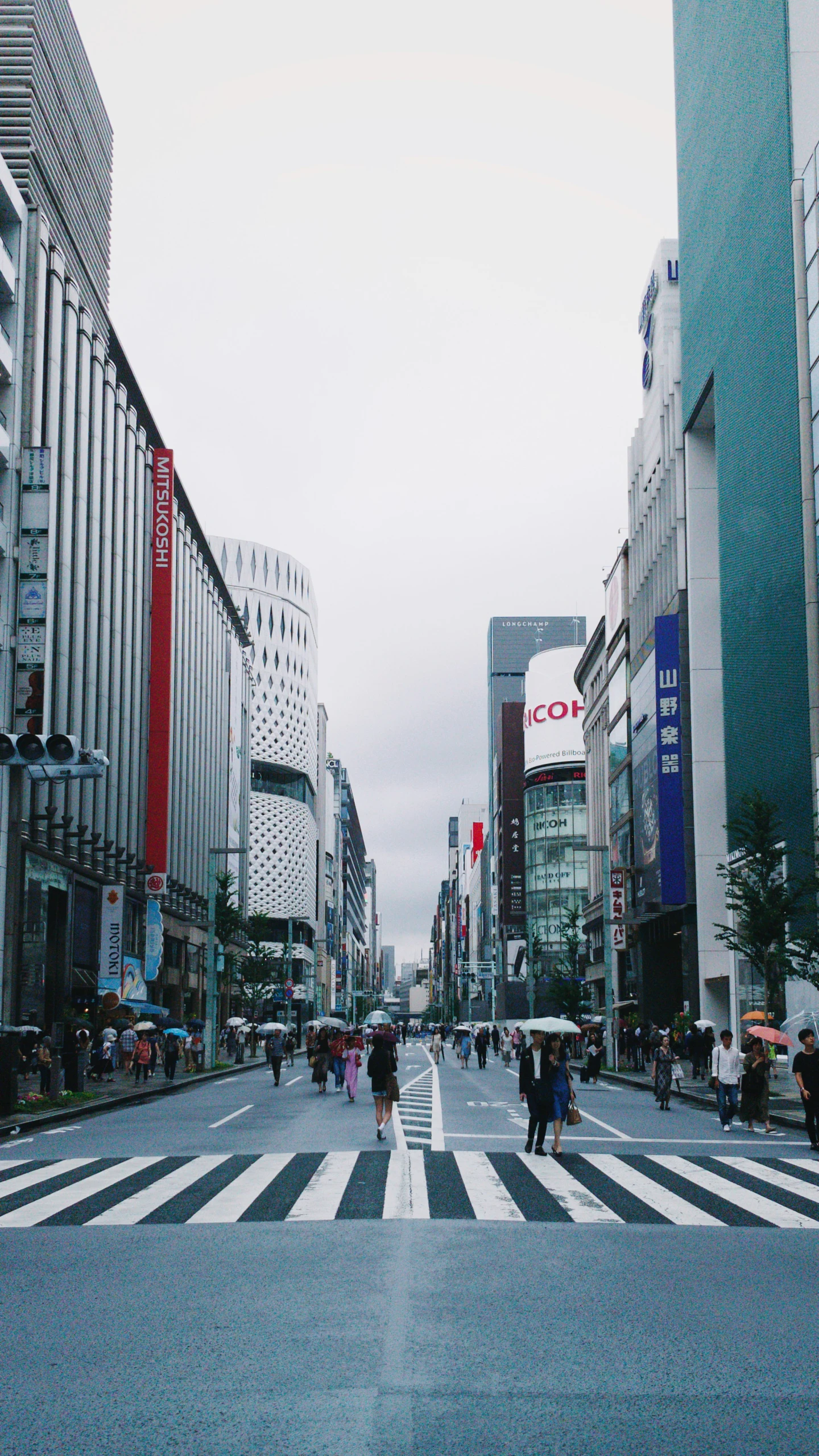 people walking on a city street with tall buildings