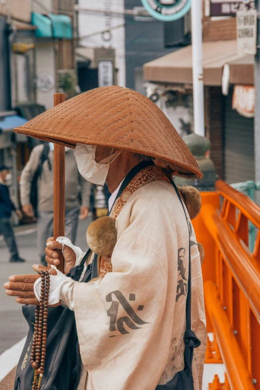 a person in a straw hat and long jacket on a street