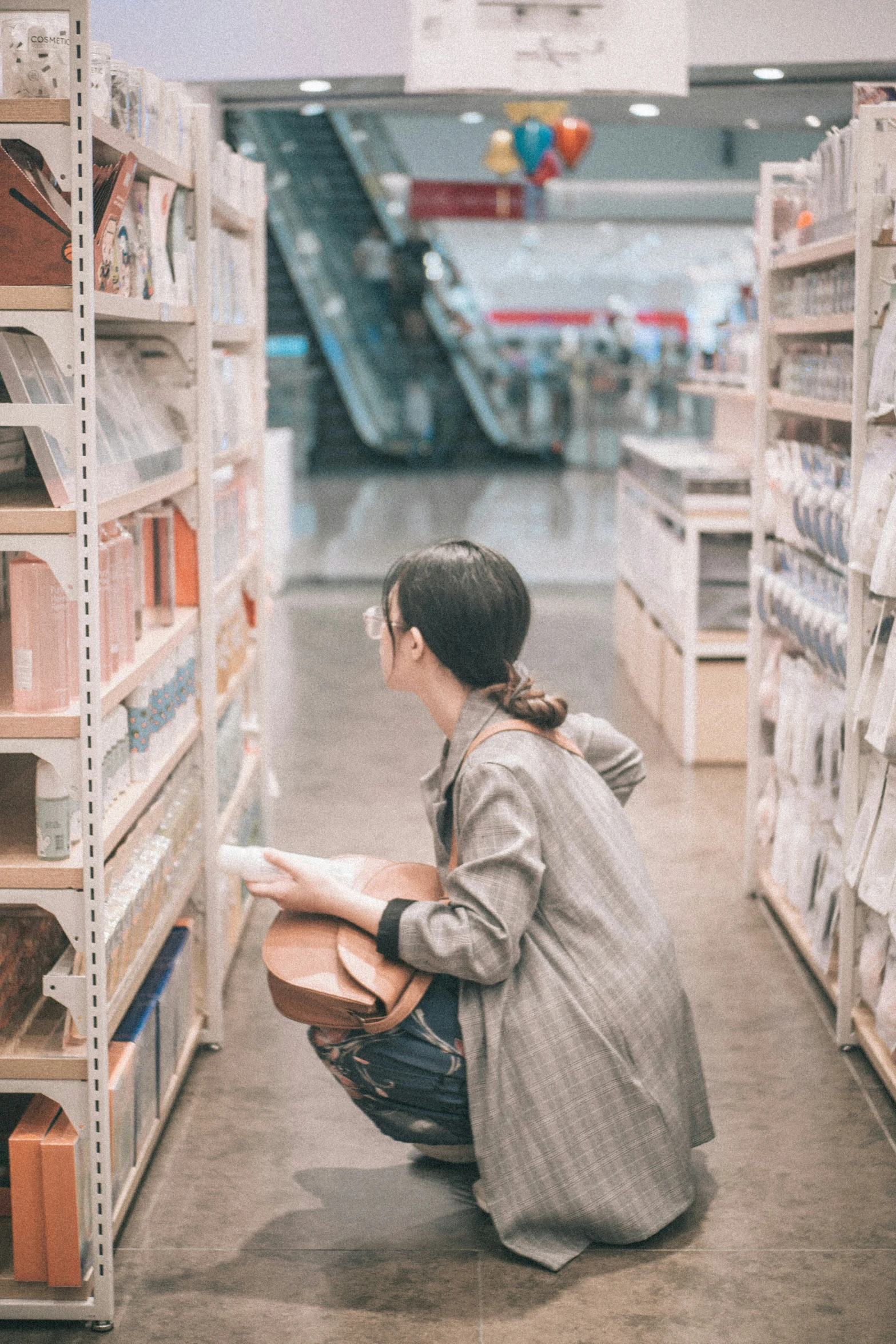 a woman is reading in the middle of a book aisle