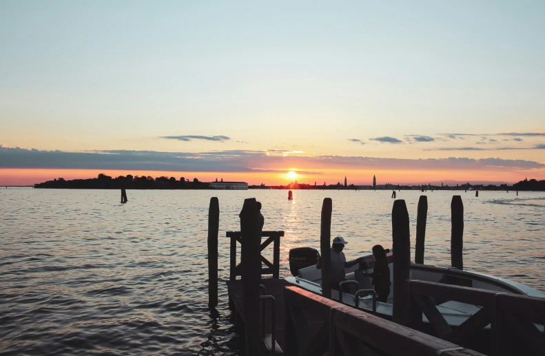 a sunset over some water with boats parked on the pier