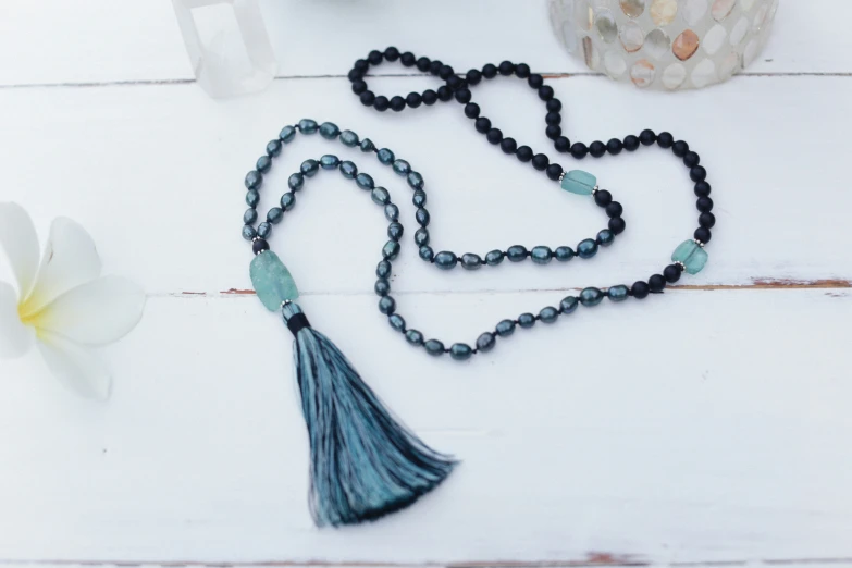 a tasseled necklace, a white flower, and a blue glass bead necklace