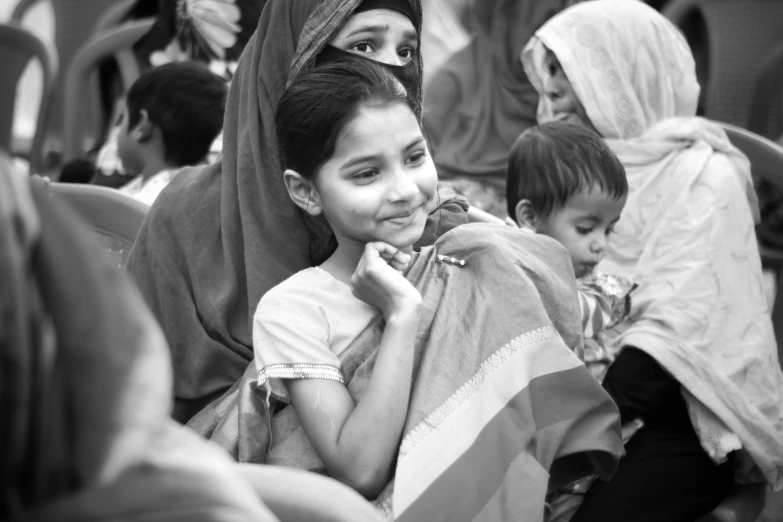 the child smiles as she sits beside two other children