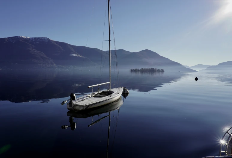 an empty boat floating on the water next to mountains