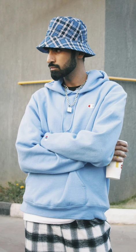 a man in a blue hoodie is standing with his arms crossed