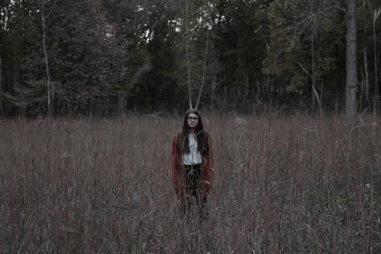 a woman standing in a grassy field in the woods