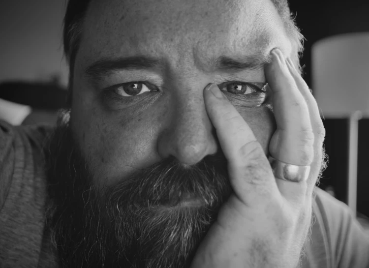 a black and white po of a man with hands on his face