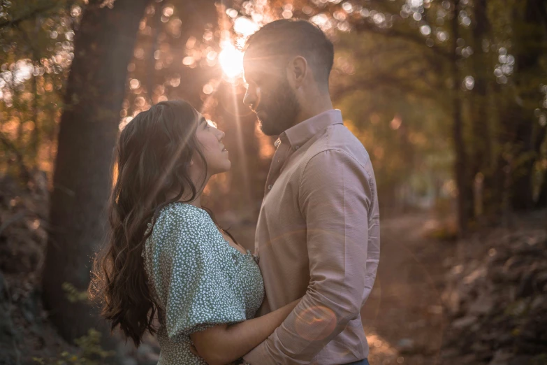 an engaged couple standing in the middle of a forest together at sunset