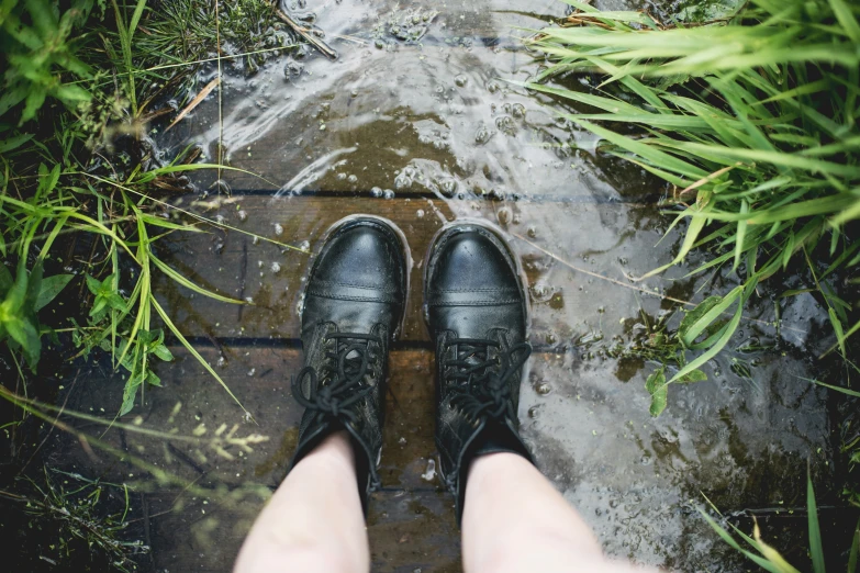 a person stands on a wooden platform above a stream