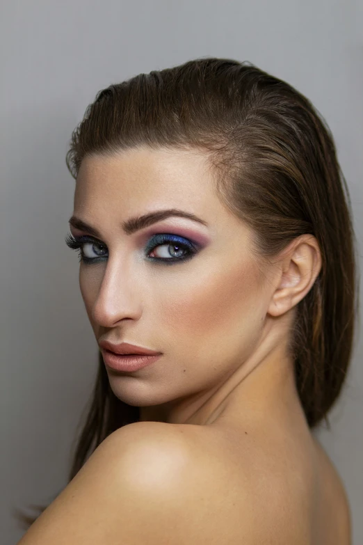 woman with makeup posing for the camera and holding her shoulder up