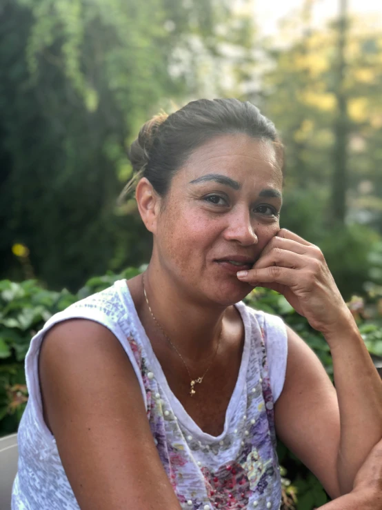 a young woman with a toothy expression sitting outside