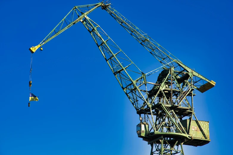an iron crane is seen while a blue sky is visible
