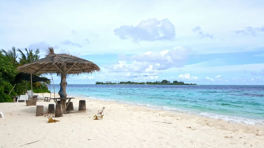 two people on the beach under a small umbrella