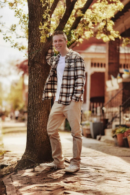 the man is smiling leaning against the tree