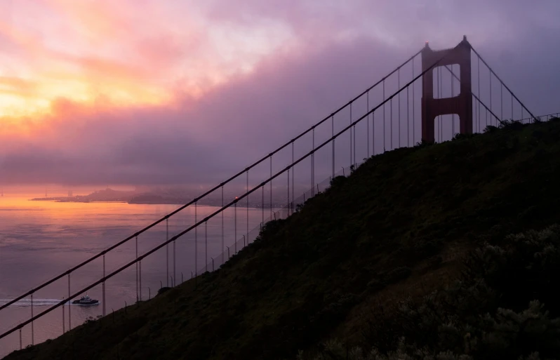 a large long bridge on a hill near a body of water