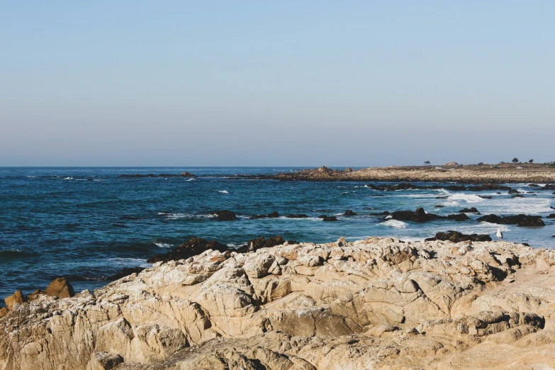 an ocean landscape with a rock shore and blue sky