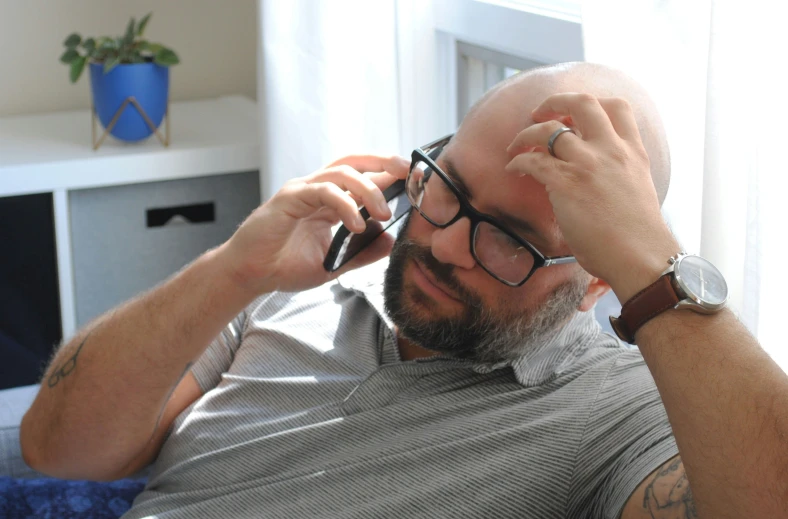 a bald man wearing glasses and a watch on his wrist