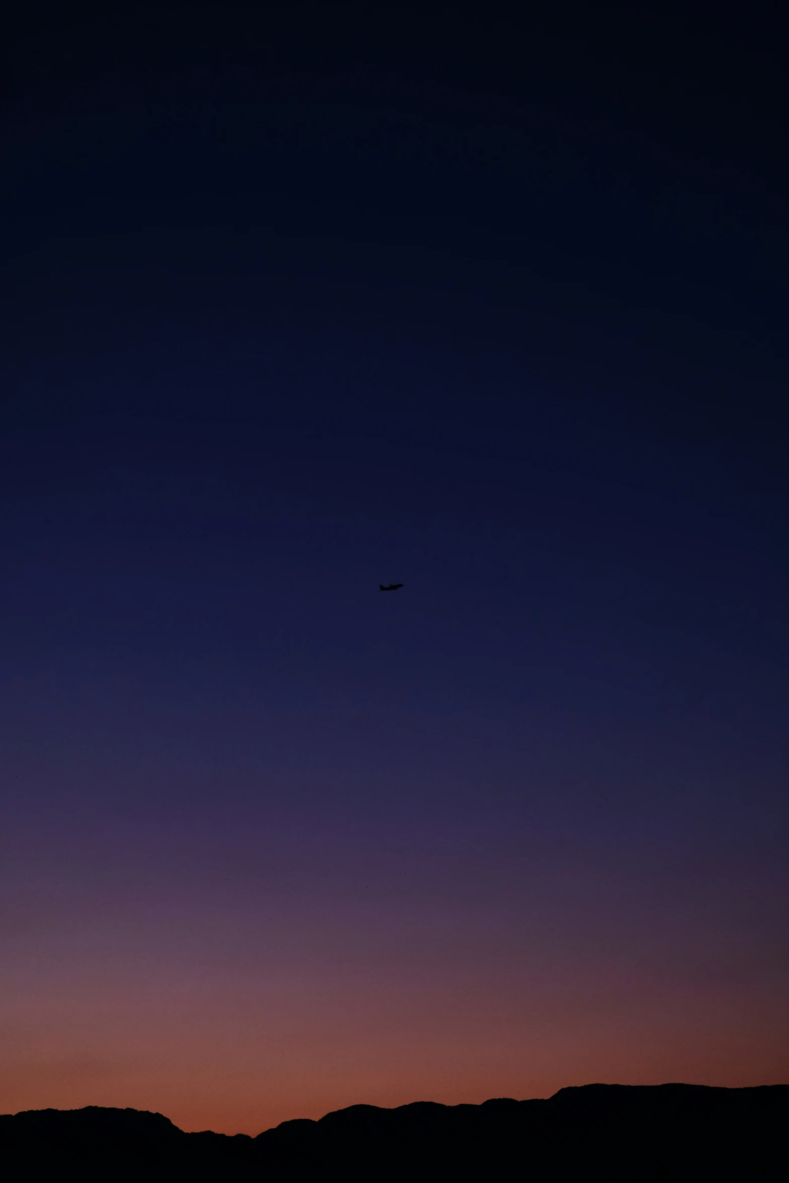 the dark blue sky is lit up by a plane flying over