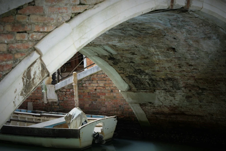 a small boat moored under a brick bridge