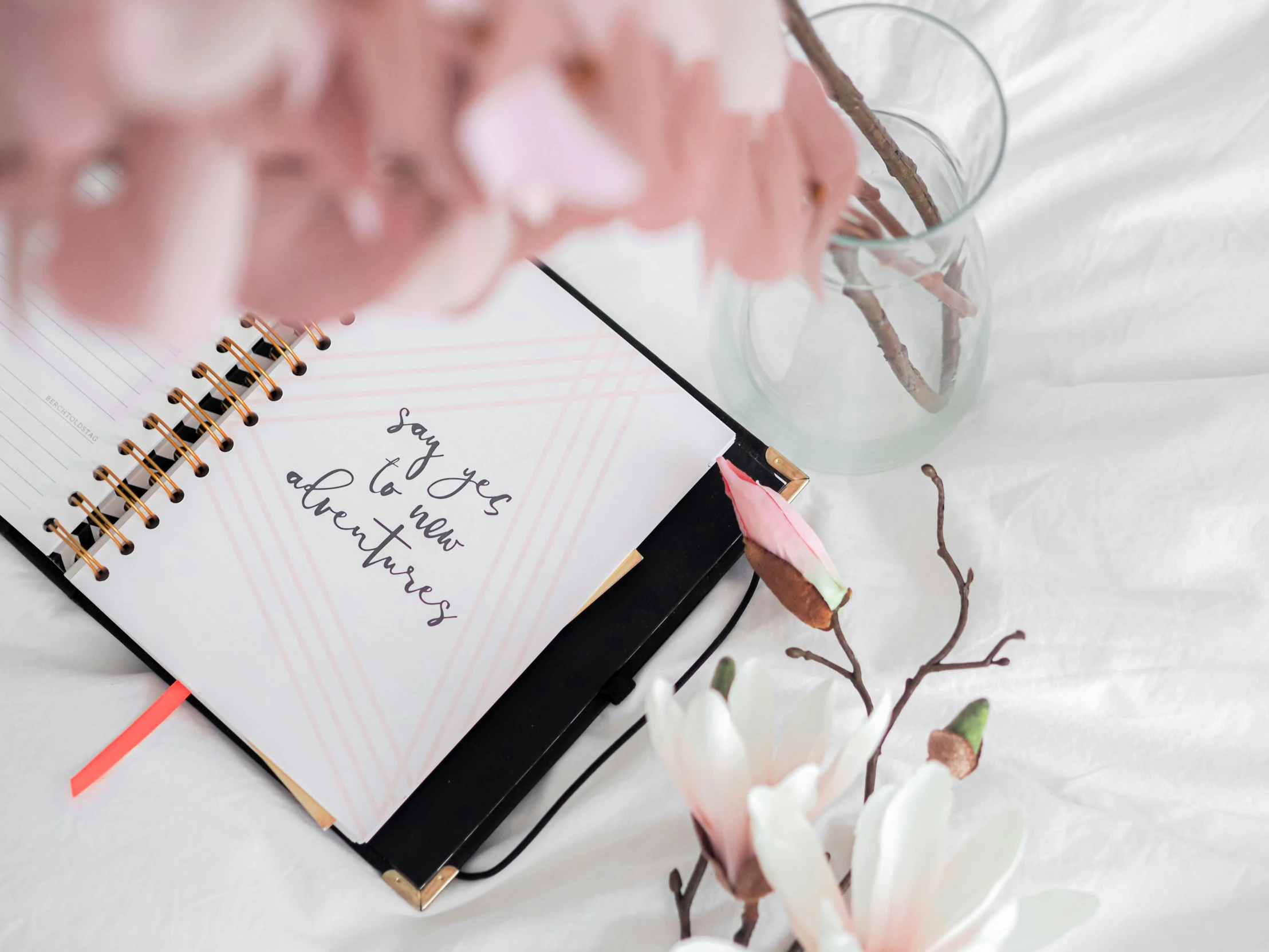 a notepad that is placed on a bed next to flowers