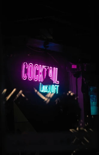 neon signage with cocktail capital in bright purple and green