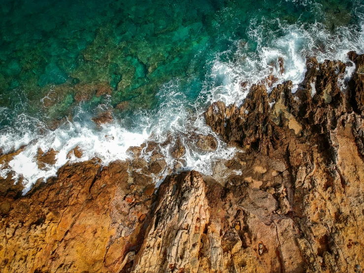 an aerial view of the ocean next to a rocky cliff