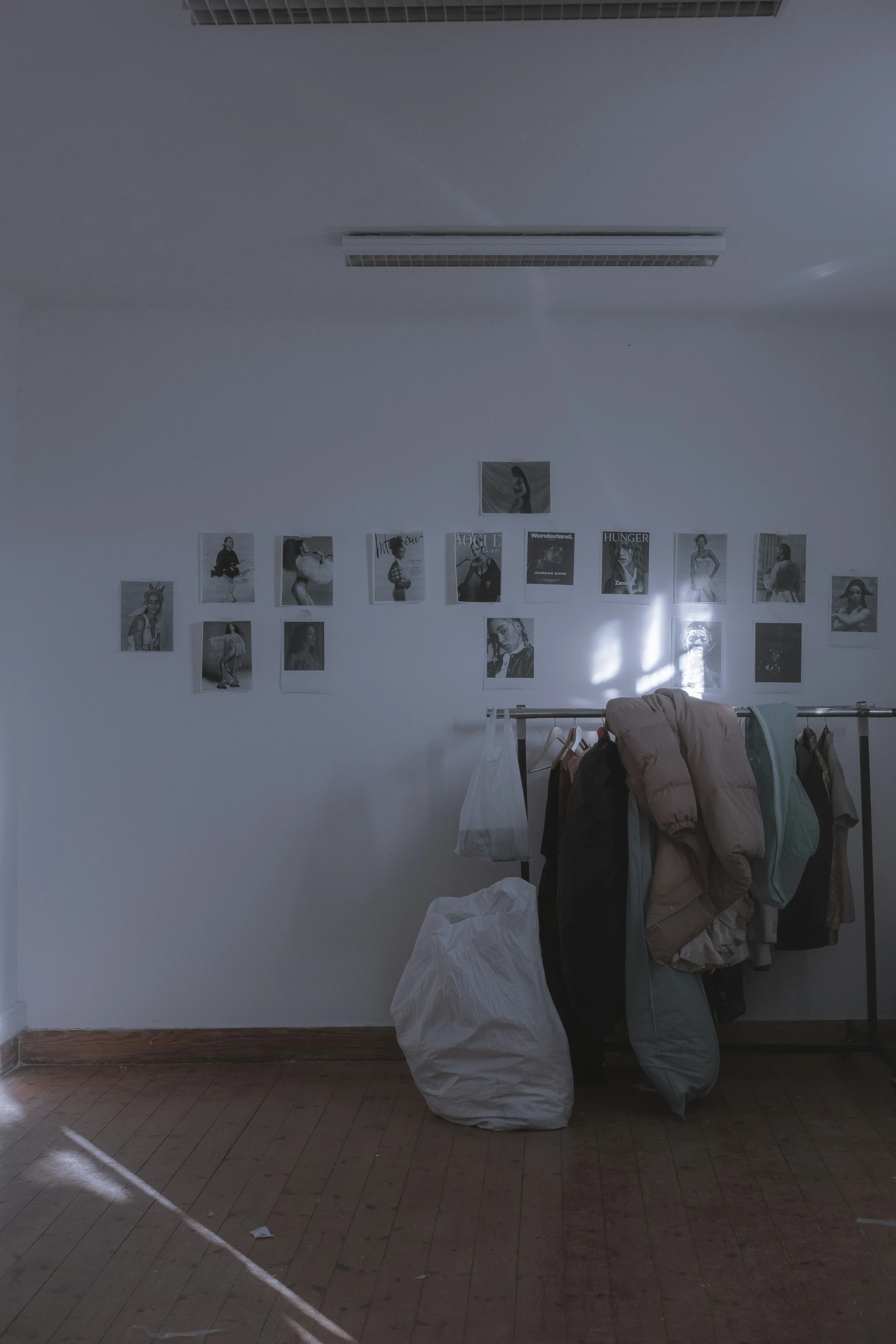 a pile of clothes sits near clothes hanging in an apartment