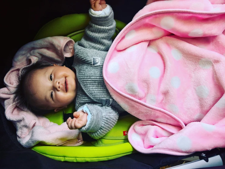 a baby sits in a pink and green car seat