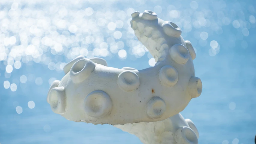 a white statue with bubbles coming out of the ocean