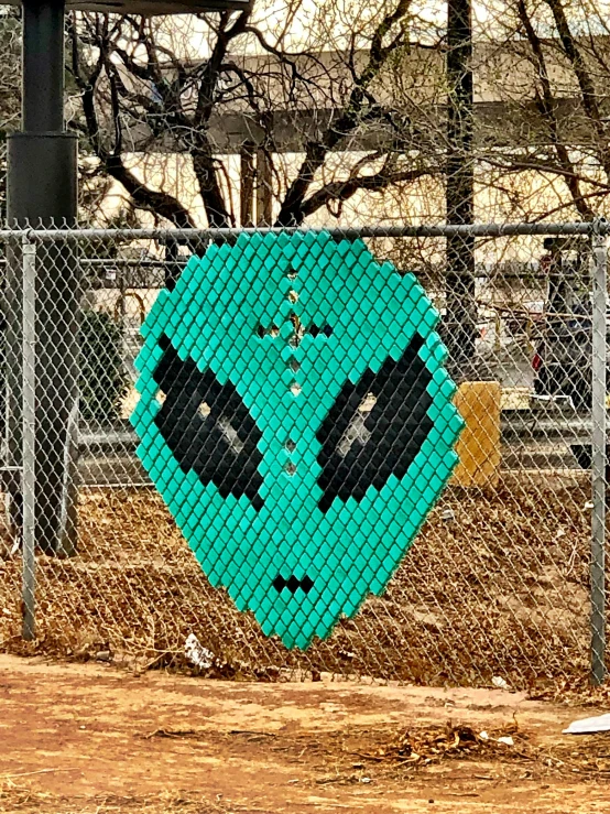 a fence has a painting of a blue alien head behind it