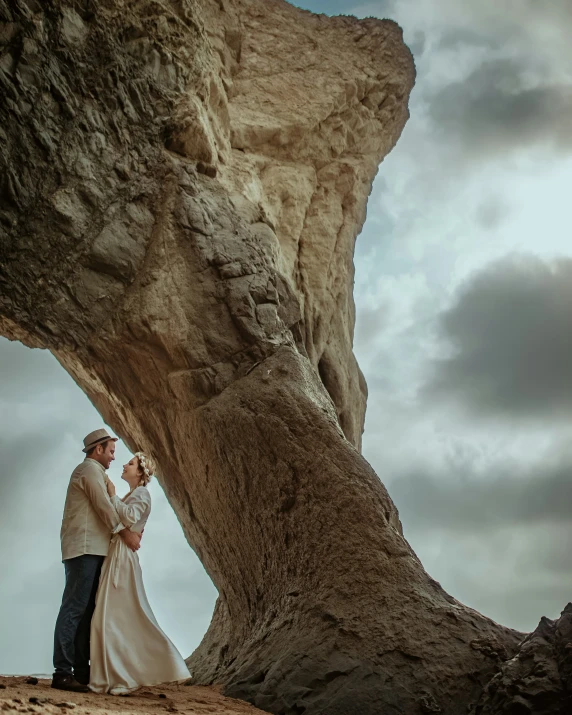 a man and woman standing under an upturned tree