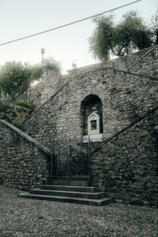 a staircase is made from cobblestone and has a large stone building behind it