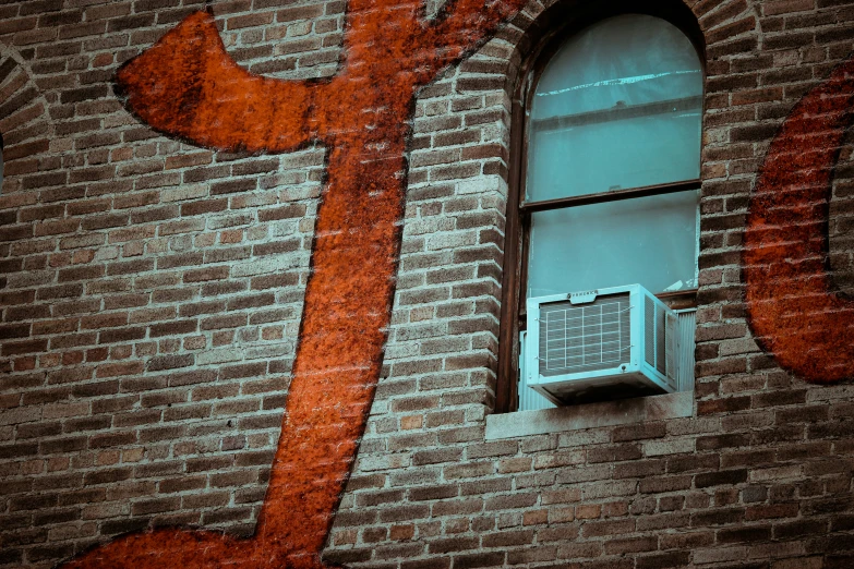 an old brick building has a window and is painted with orange