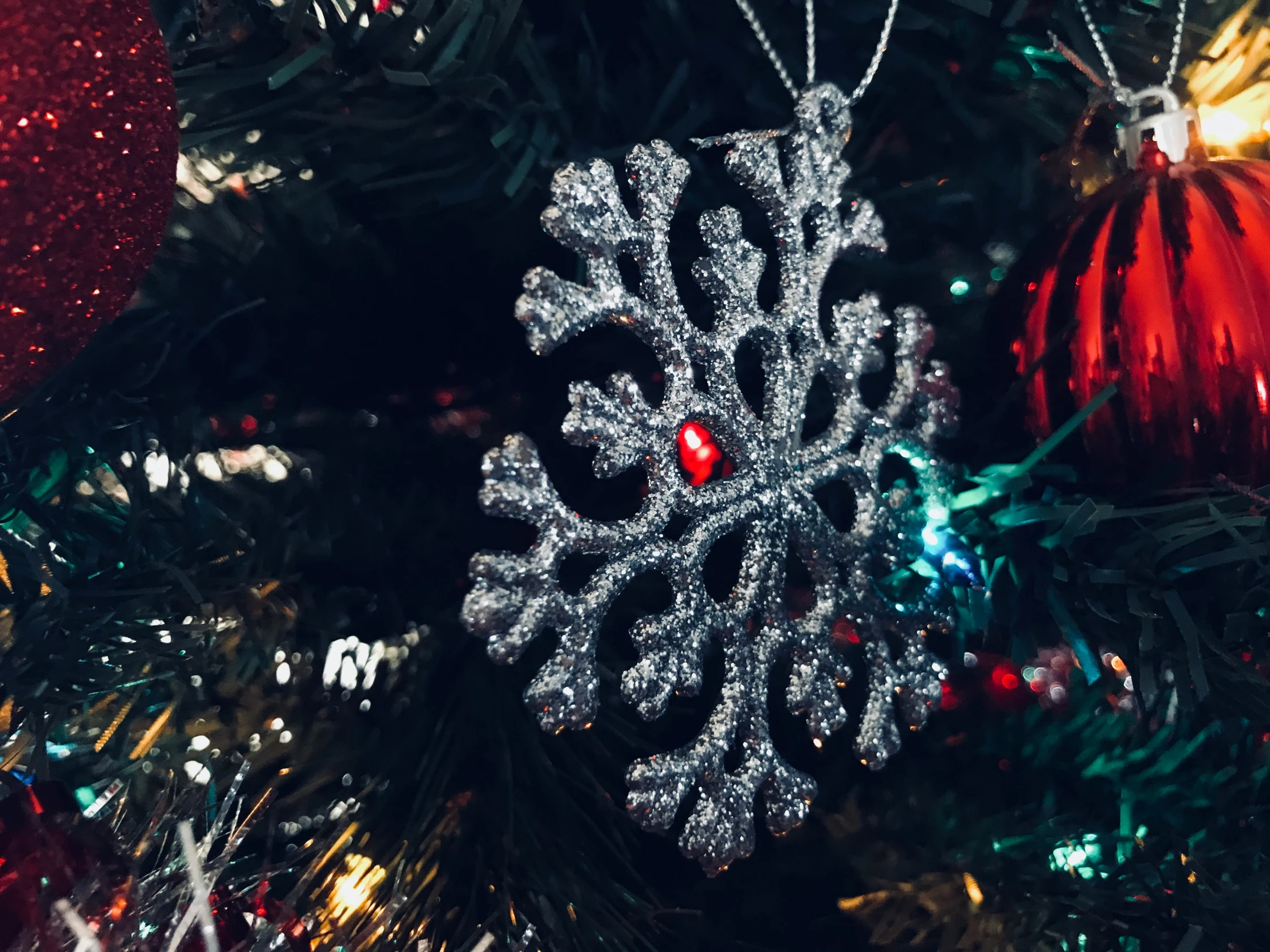 silver and red snowflake ornament hanging from a christmas tree