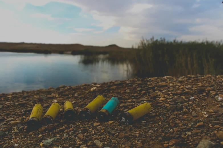 yellow and blue plastic bottles resting on a rocky beach next to water