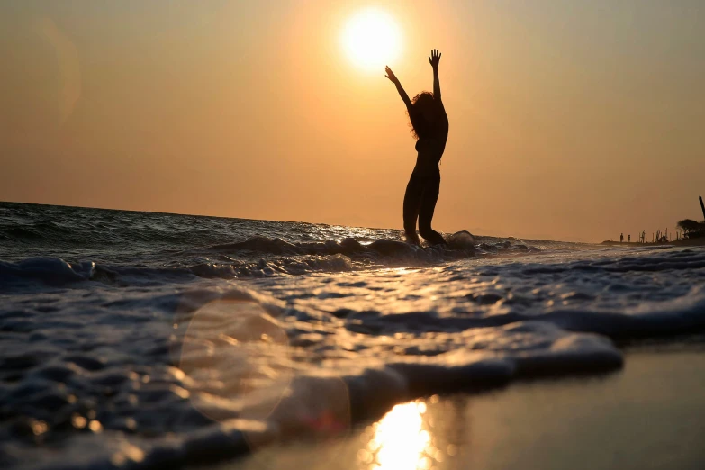 the girl in silhouette stands on the surfboard in the ocean