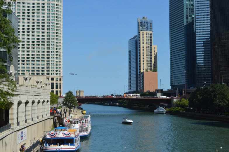 several boats traveling on the river under tall buildings