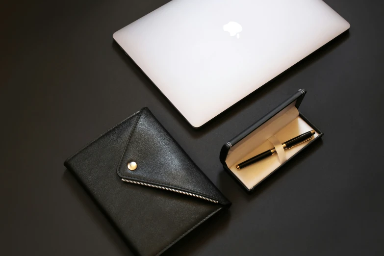 a white laptop and a black wallet sitting on top of a table