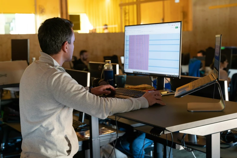 a man sitting at his desk working on a laptop