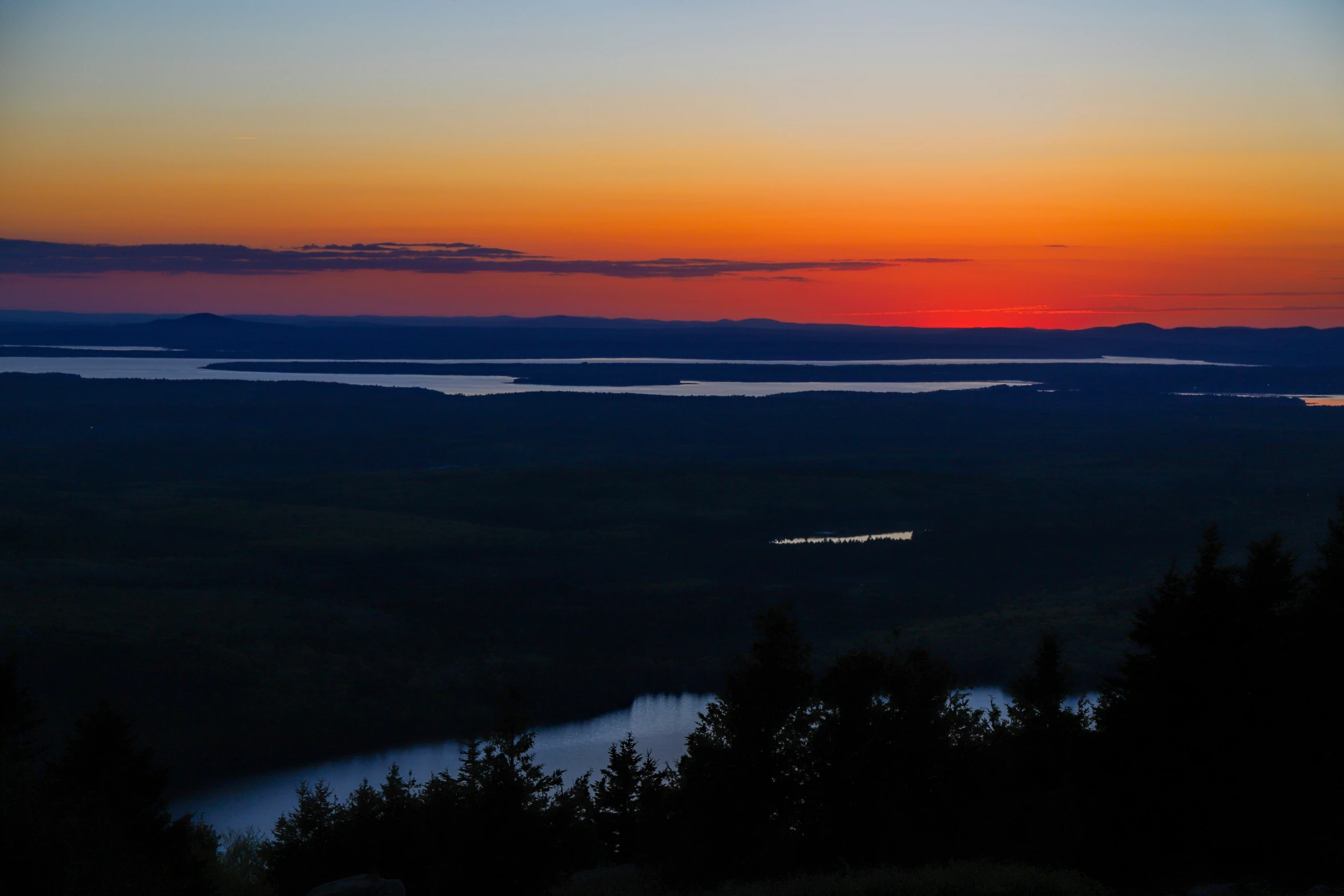 the sun sets over some water and land