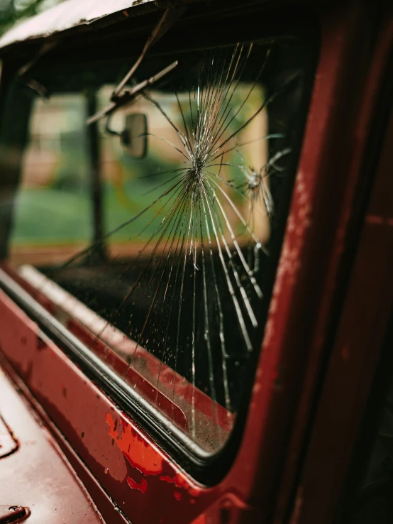 shattered glass sitting on the window of a red vehicle