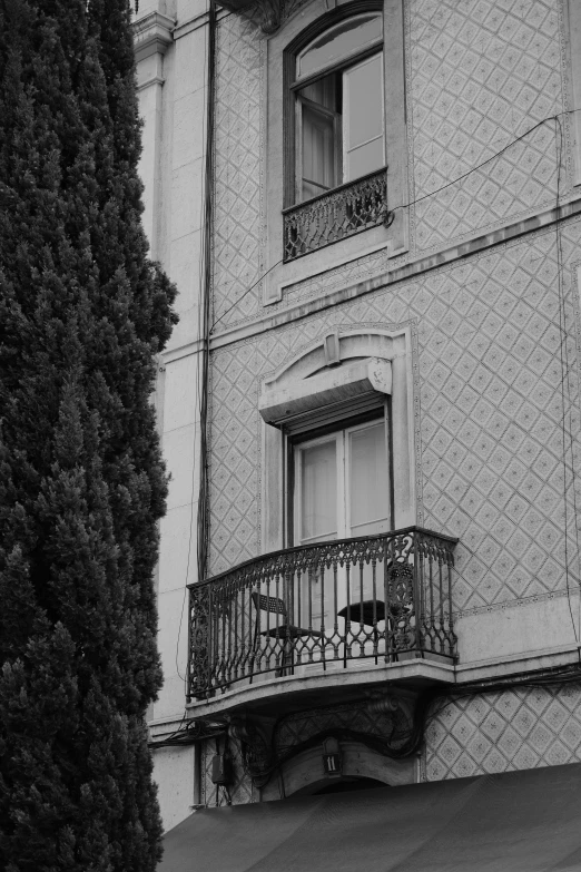 a balcony has a table and chairs under a window