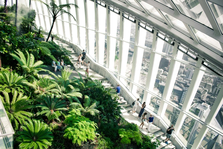 a large open building with lots of plants and people standing in front