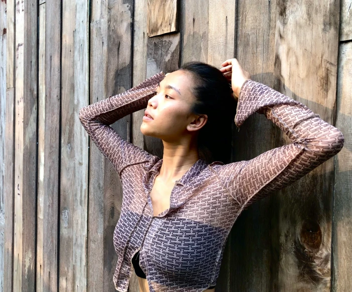 a woman is leaning against a wooden wall and posing