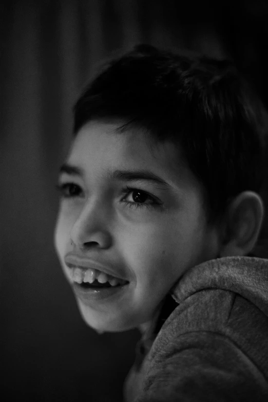 a smiling boy with dark colored hair and an unkempt smile