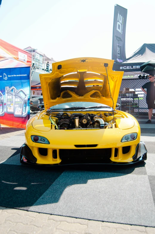 yellow sports car with hood open on a street