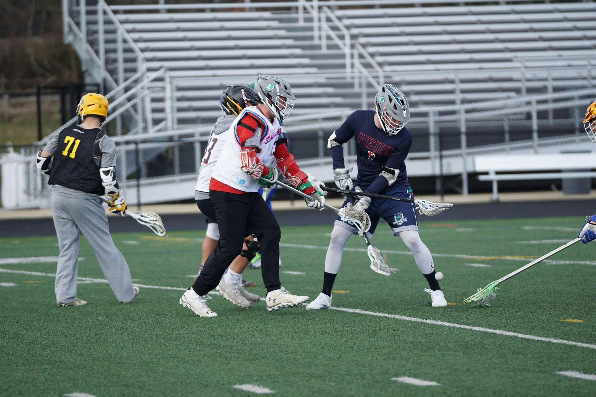 three boys in uniforms play lacrosse on the field