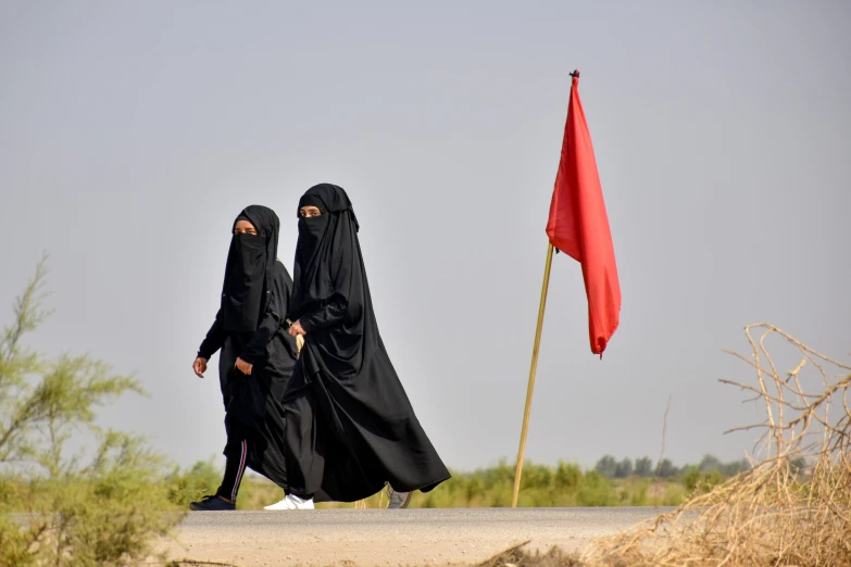 two women wearing black dresses with a red flag next to them