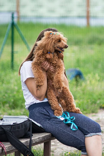 a woman sitting on top of a bench holding a dog